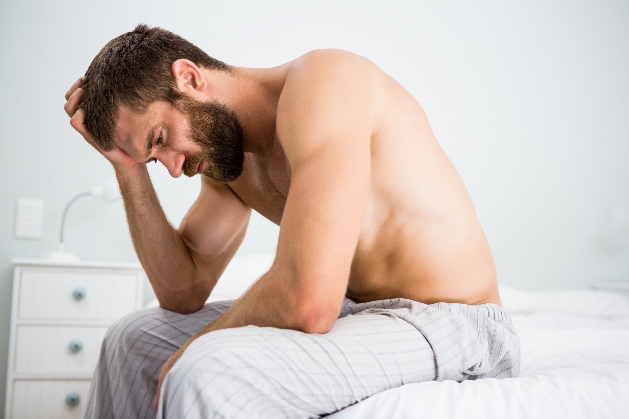 Depressed man on bed with hand on head